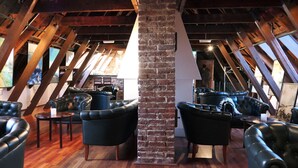 An attic-style room with exposed wooden beams, brick walls, and leather sofas. - Home Hotel Amanda (Haugesund)