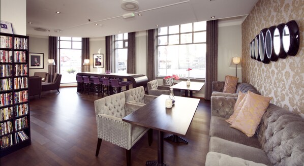 A spacious lobby with a bar area, seating, and a bookshelf.