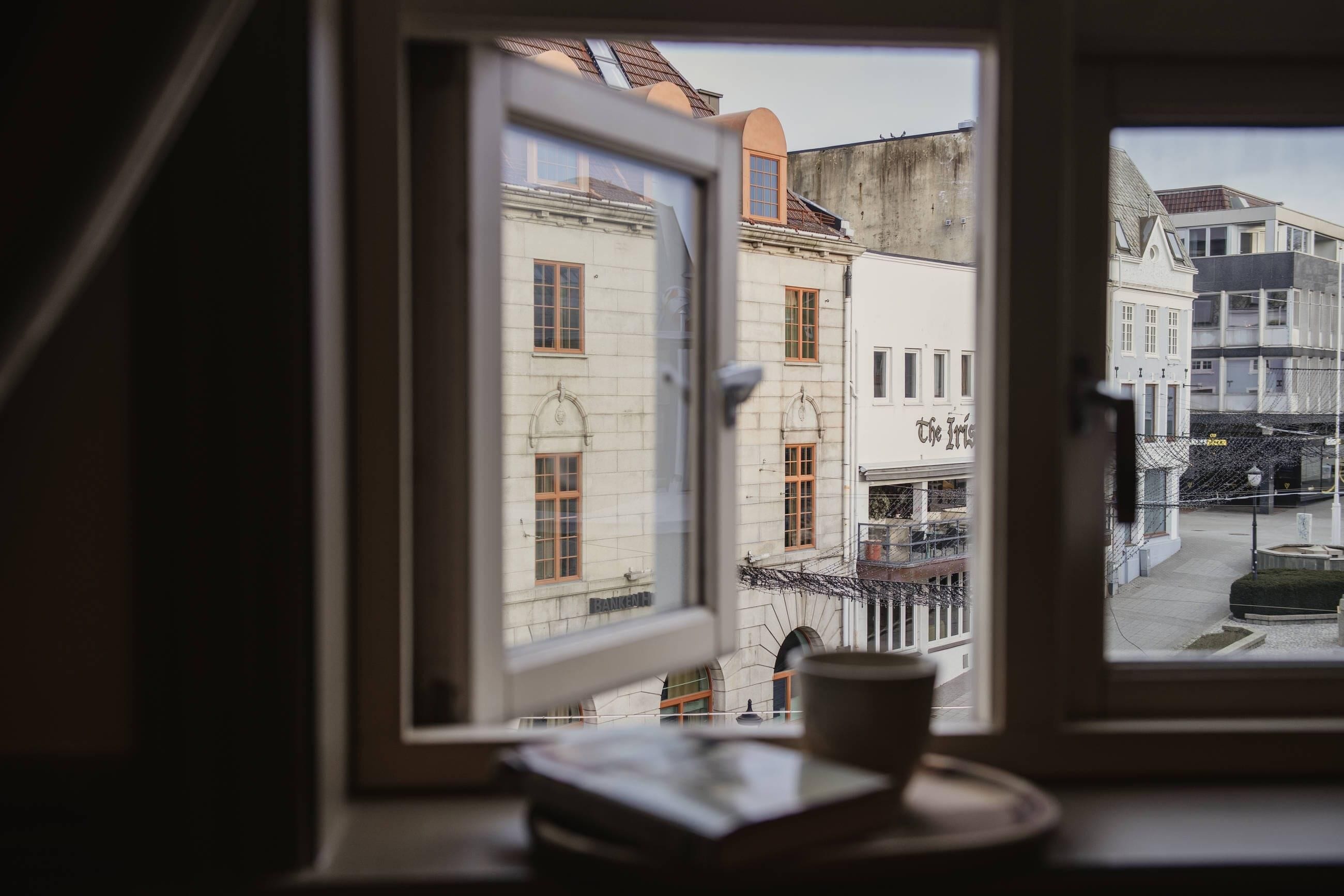 Una habitación con vista a edificios históricos a través de una ventana abierta.