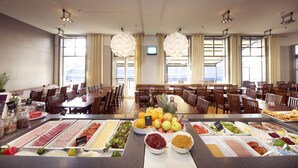 A buffet setup with various food items and a seating area with tables and chairs. - Home Hotel Amanda (Haugesund)
