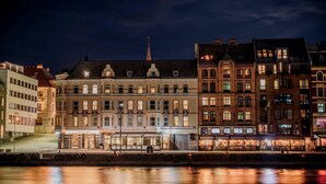 A waterfront hotel with multiple stories, large windows, and a prominent church spire in the background. - Home Hotel Amanda (Haugesund)