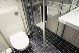 Un baño con inodoro, cabina de ducha de vidrio y lavabo.