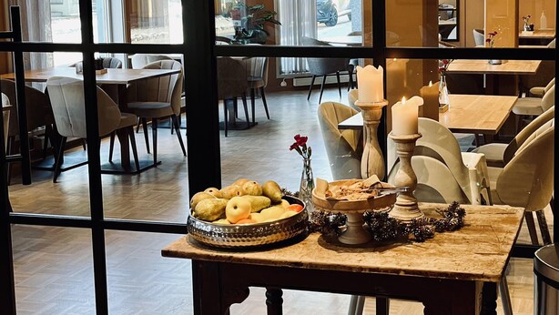 A dining area with a table set for two, featuring a decorative centerpiece with candles and a floral arrangement.