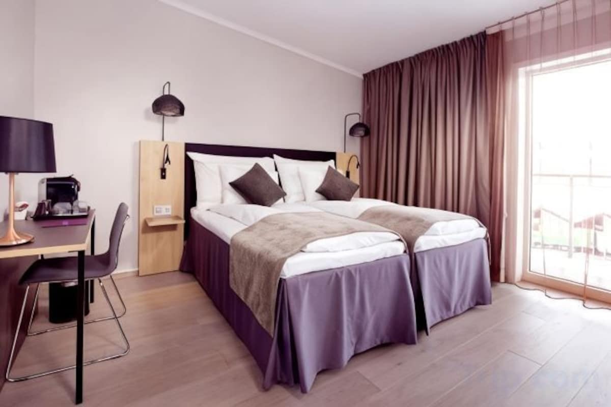 Een hotelkamer met een bed, bureau, stoel en uitzicht op de omgeving.