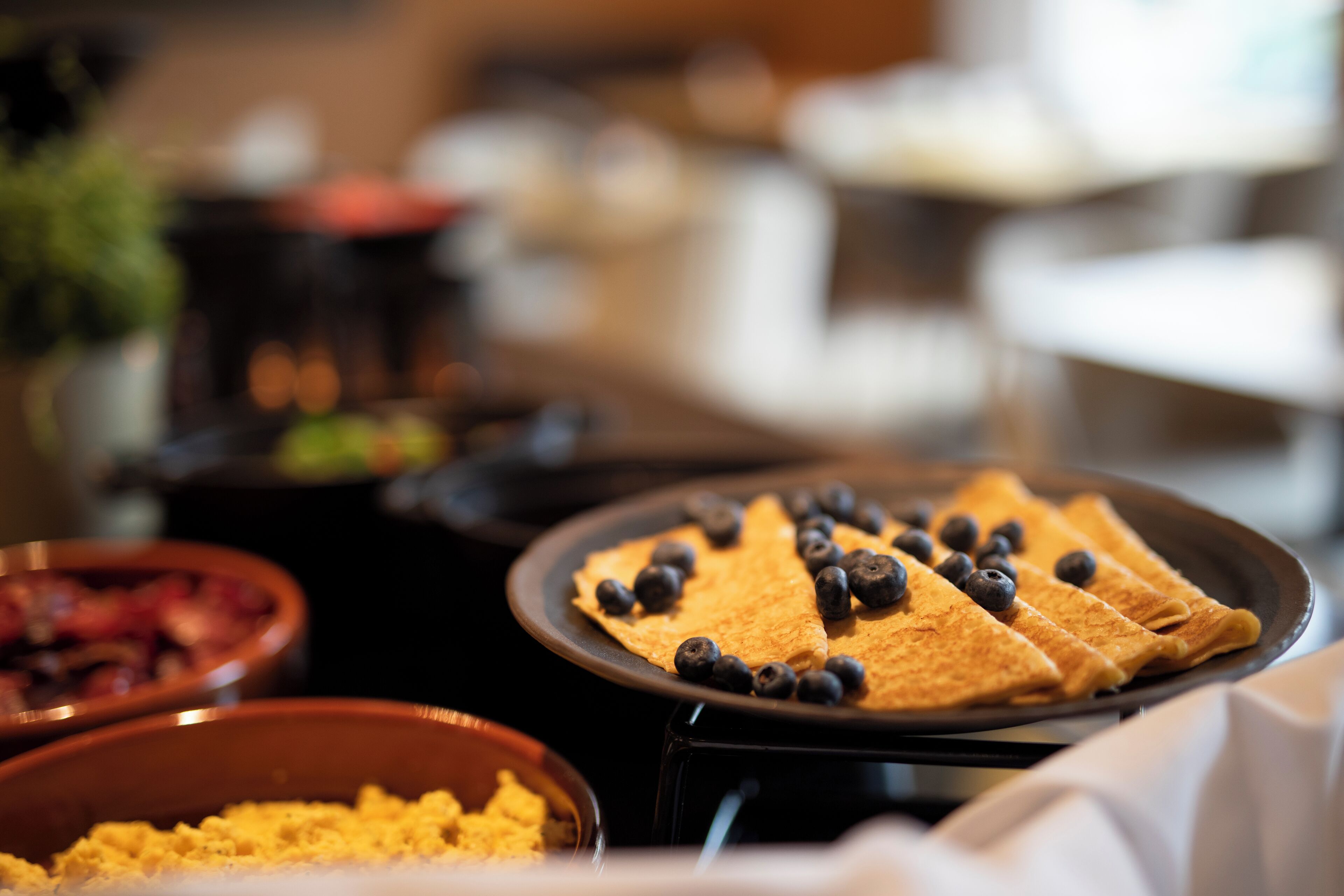 Un buffet de petit-déjeuner proposant des crêpes garnies de myrtilles et divers autres plats.