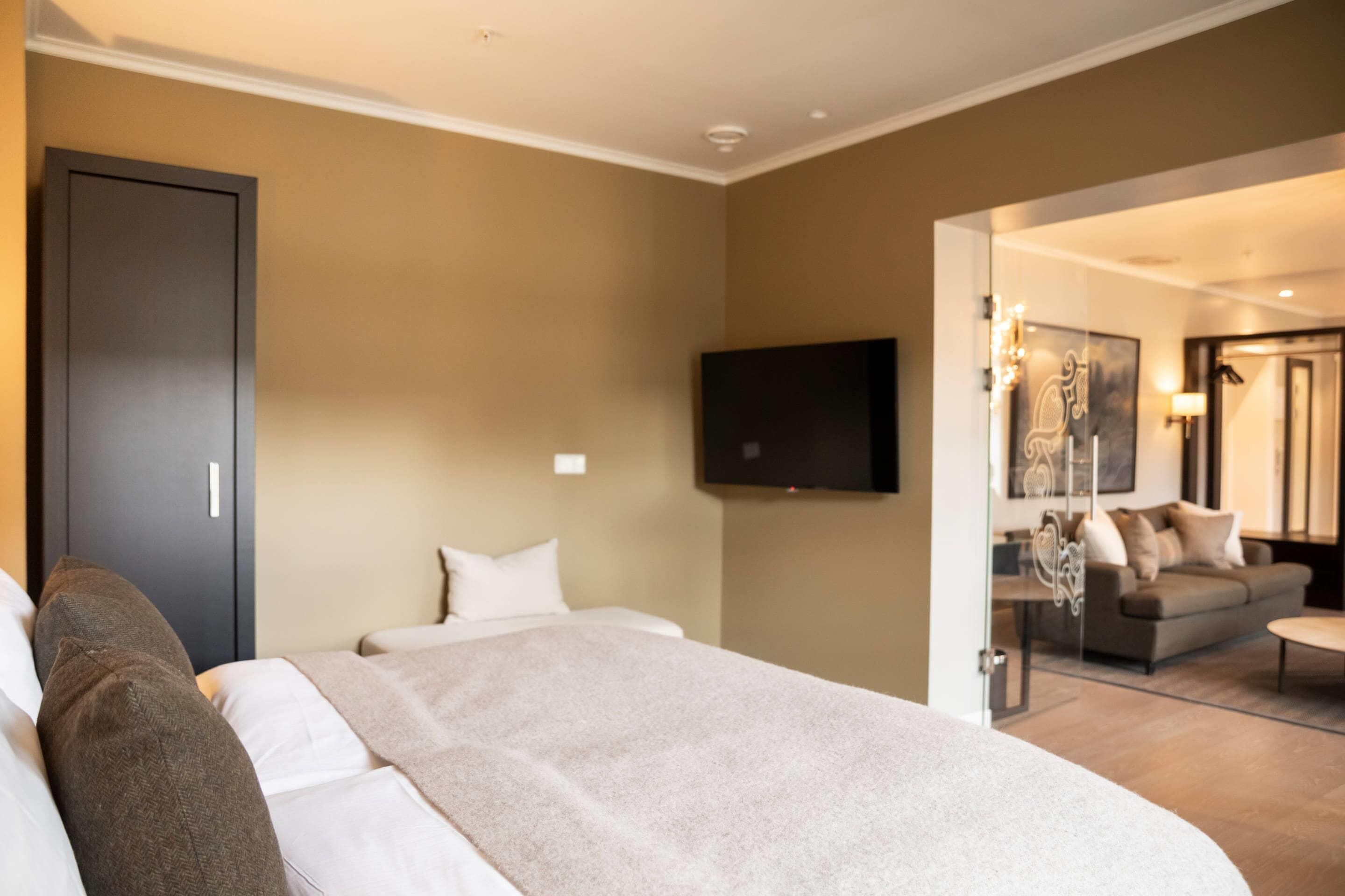 Una habitación de hotel con cama, televisión, sofá y espejo.