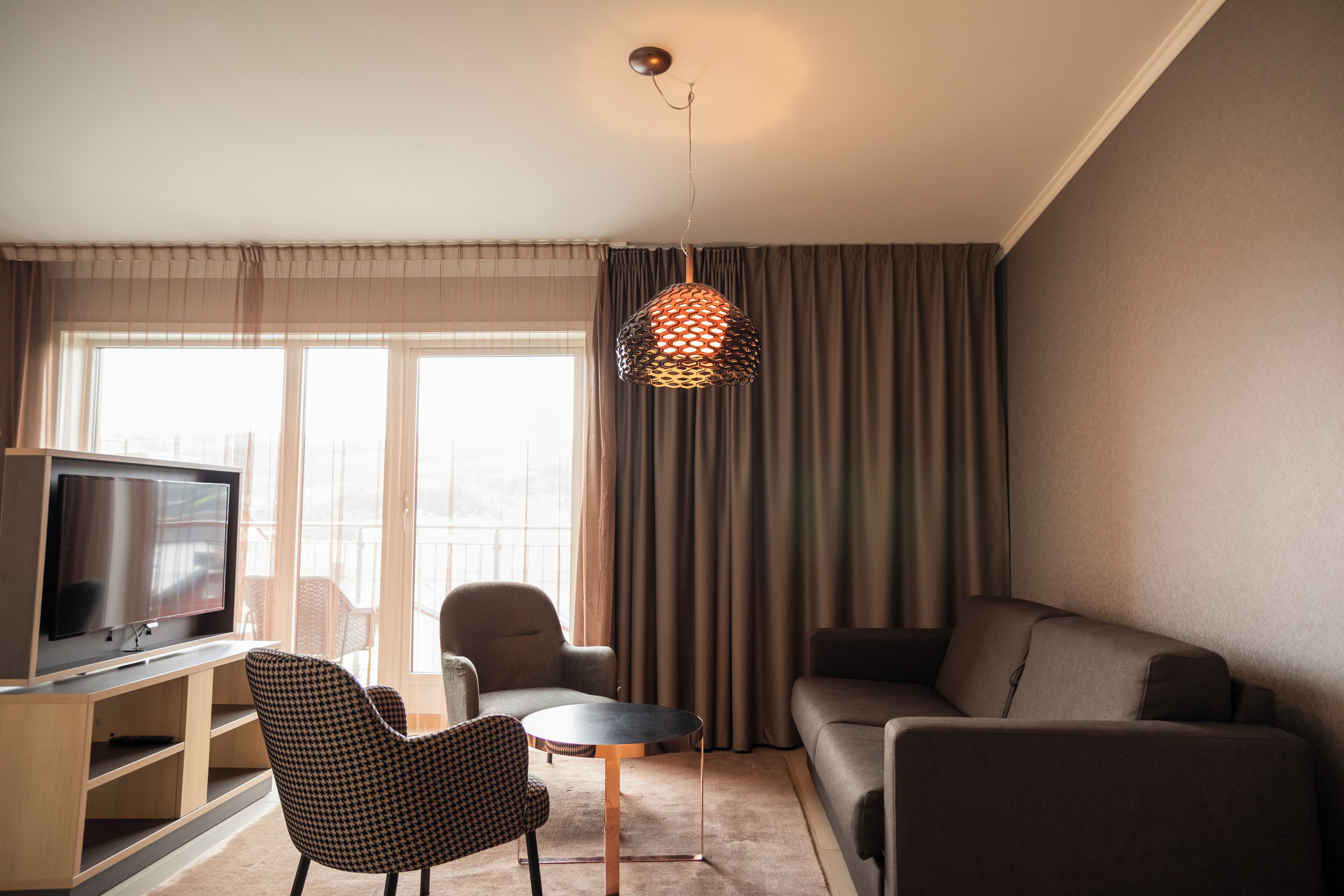 Una sala de estar moderna con un televisor de pantalla plana, un sofá, una silla y una pequeña mesa.