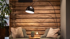 A cozy seating area with two armchairs, a small round table with a lamp, and a potted plant.