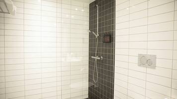 A bathroom with white and black tiles, a shower with a handheld showerhead, and a towel rack.