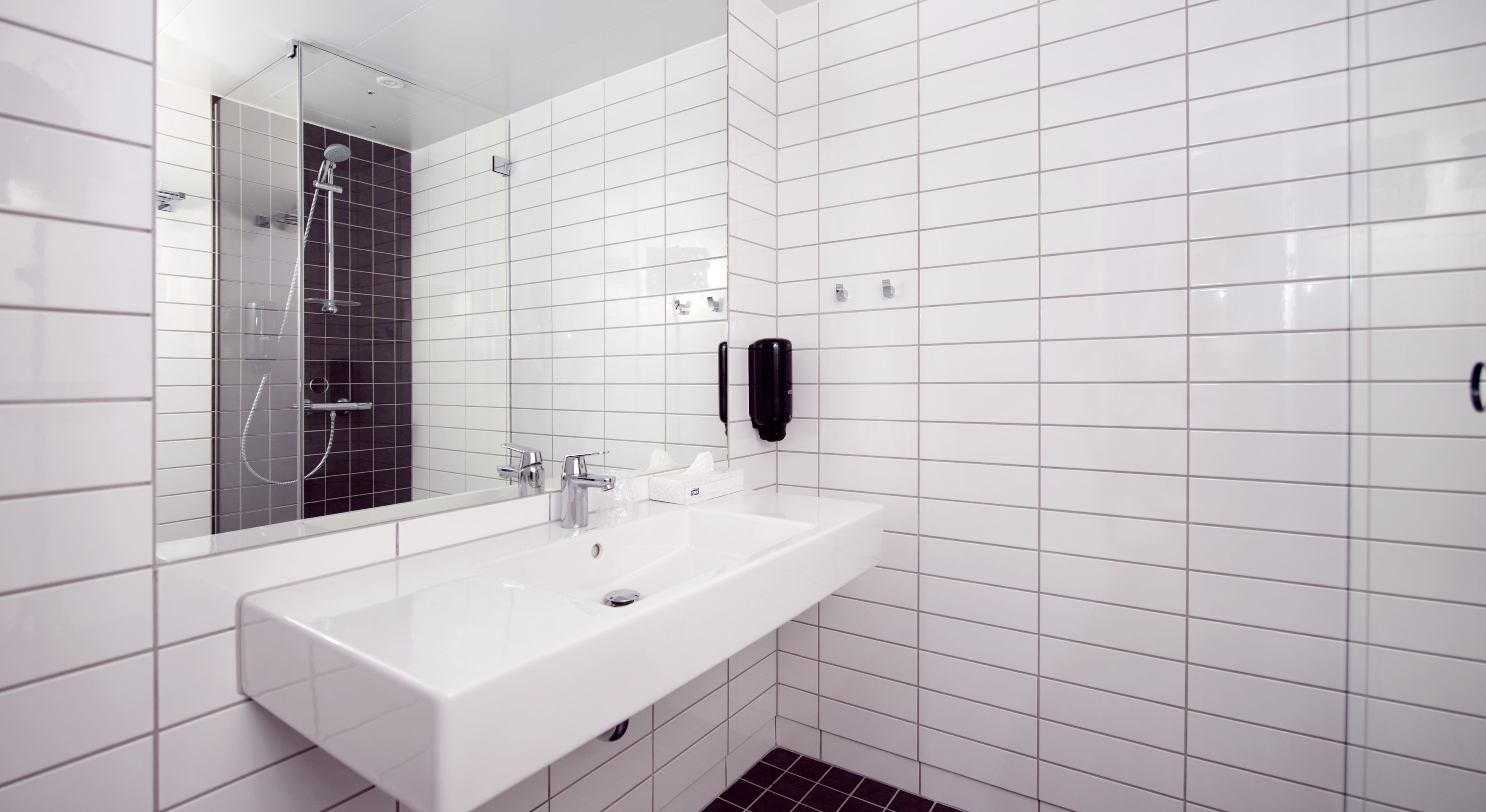 Ein modernes Badezimmer mit einem weißen Waschbecken, einem Spiegel und einer schwarzen Handbrause.