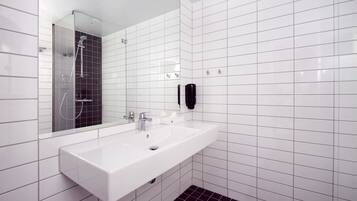 Ein modernes Badezimmer mit einem weißen Waschbecken, einem Spiegel und einer schwarzen Handbrause.