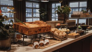 Een buffet met diverse gerechten, houten serveerplanken en potplanten.