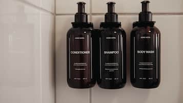 Three black bottles of Home Hotel products: conditioner, shampoo, and body wash, each labeled with 100% vegan and 280 ml.