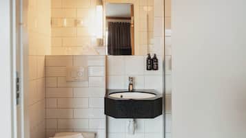 A bathroom with a toilet, sink, mirror, and two bottles of shampoo.