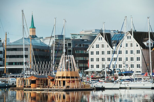 A marina with boats docked, a wooden structure, and a building with a green spire in the background.