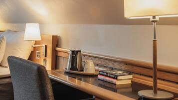 Une chambre d’hôtel avec un lit, une table de chevet avec une lampe, une machine à café, une tasse et un livre.