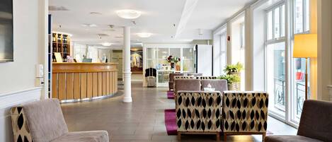 A spacious lobby with seating areas, a reception desk, and large windows providing natural light.