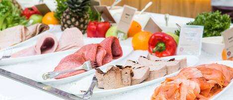 A buffet table with various food items including meats, fruits, and vegetables.