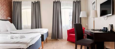 Una habitación de hotel con dos camas, un escritorio, una silla, un televisor y cortinas.