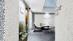 A modern interior with a stone-textured wall, a seating area with a cushioned chair and table, and a small plant arrangement. - Best Western Plus Hotel Bakeriet (Trondheim)