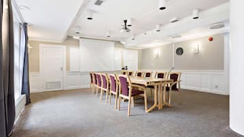 Une salle de conférence dotée d’une grande table et de chaises, de murs blancs et d’un éclairage au plafond.