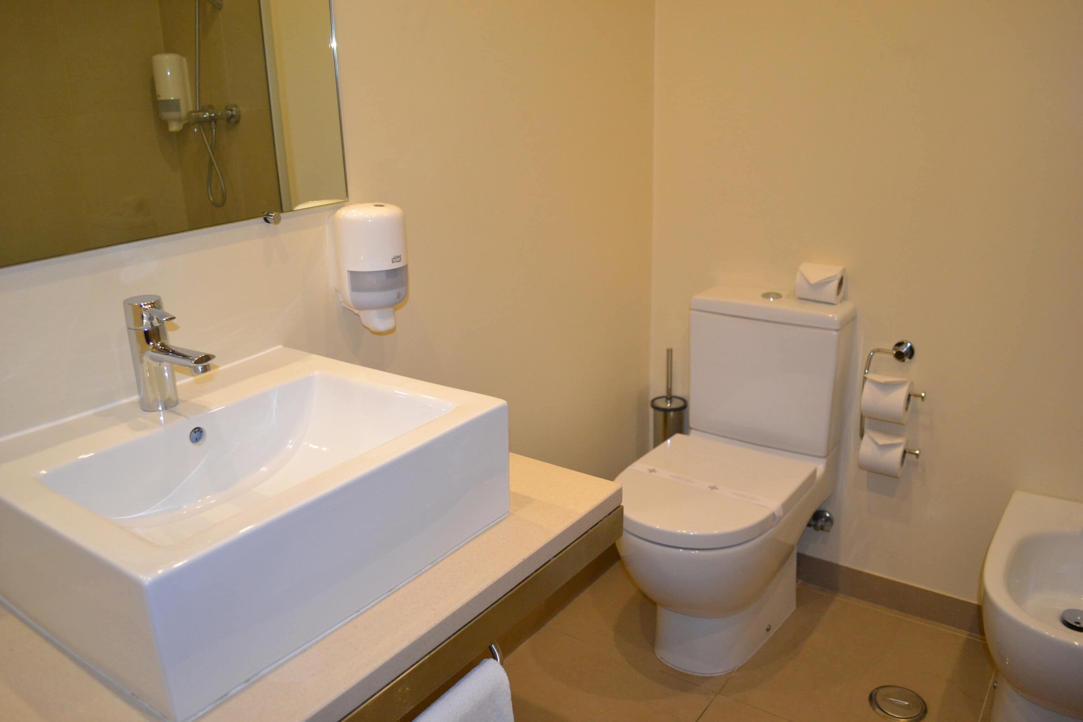 Un bagno con lavandino, WC, bidet e specchio.