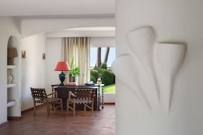 A room with a dining table, chairs, a lamp, and a view of the outdoors.