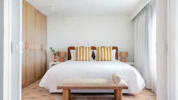 Une chambre spacieuse avec un grand lit, une armoire en bois, des lampes de chevet et un banc.