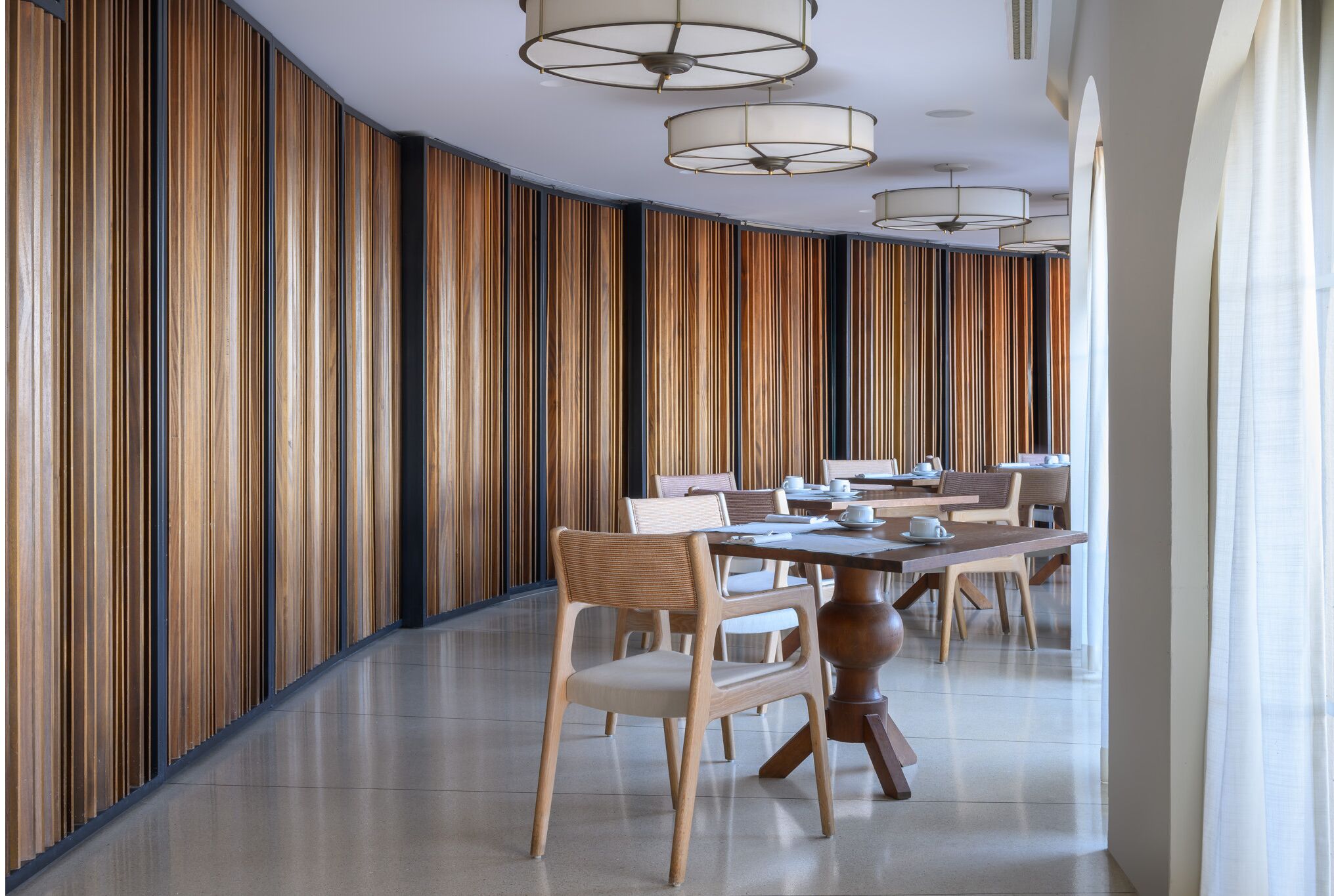 A modern dining area with wooden panel walls, a central round table, and several chairs.