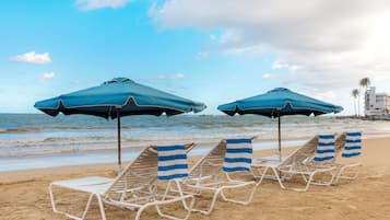 Vlak bij het strand, wit zand, parasols, strandlakens
