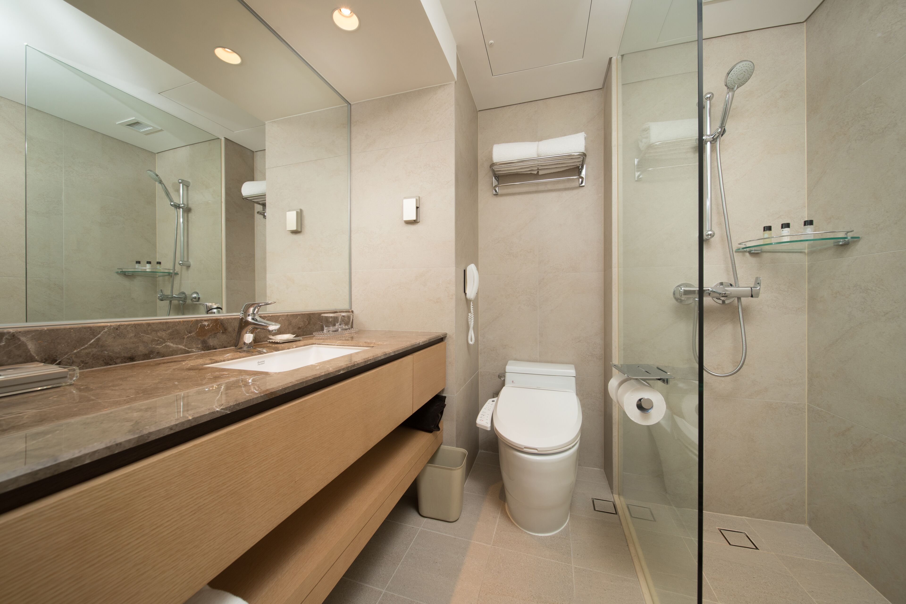 Un baño moderno con cabina de ducha de vidrio, inodoro y lavamanos con encimera de mármol.