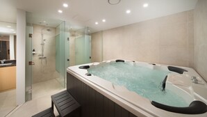 A modern bathroom with a glass-enclosed shower, a freestanding bathtub, and a wooden bench. - Jeju Sun Hotel & Casino (Jeju City)
