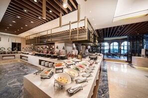 Un área de bufé con distintas estaciones de comida y un chef preparando alimentos.