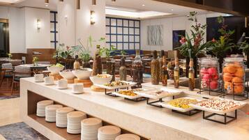 A buffet area with various food items and beverages, surrounded by tables and chairs.