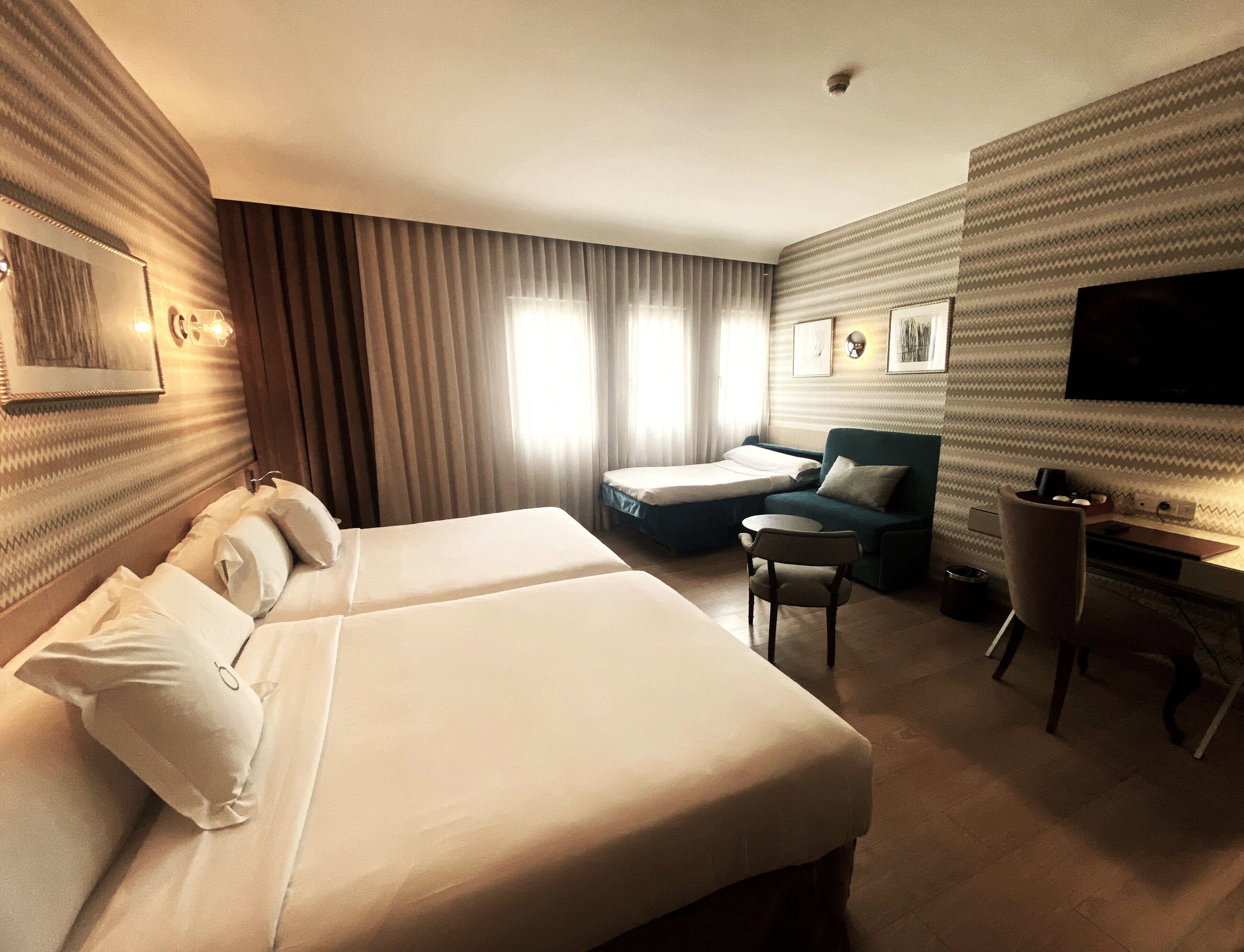 Une chambre d’hôtel avec deux lits, un bureau, une chaise et une télévision.