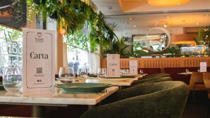 A restaurant interior with tables set for dining, QR code menus, and green upholstered chairs. - Hotel Ópera (Madrid)
