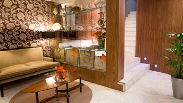 Una sala de estar con sofá, mesa de centro y objetos decorativos en estanterías.