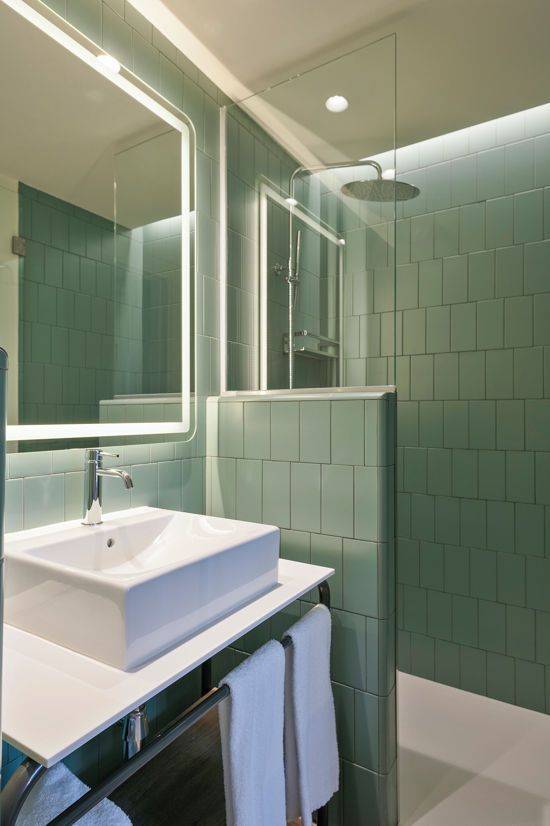 A modern bathroom with a white sink, a large mirror, and a glass-enclosed shower area.