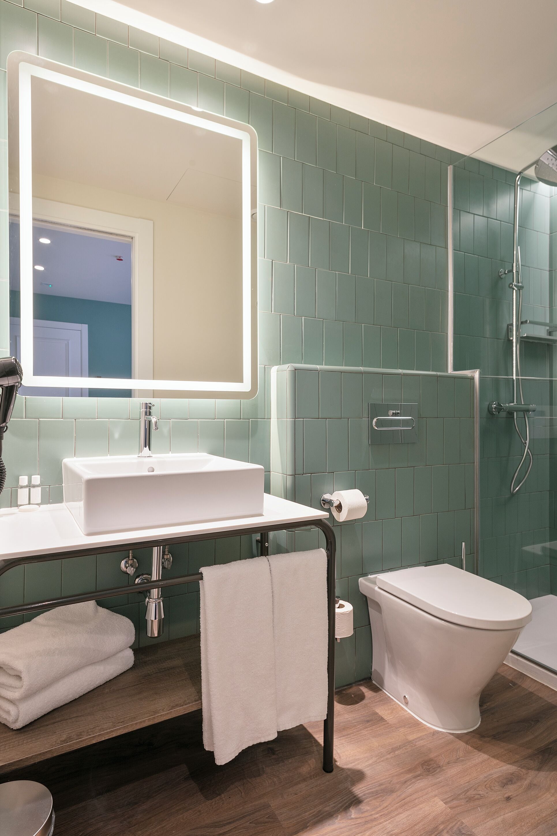 Een moderne badkamer met een grote spiegel, een witte wastafel en een douchegedeelte.