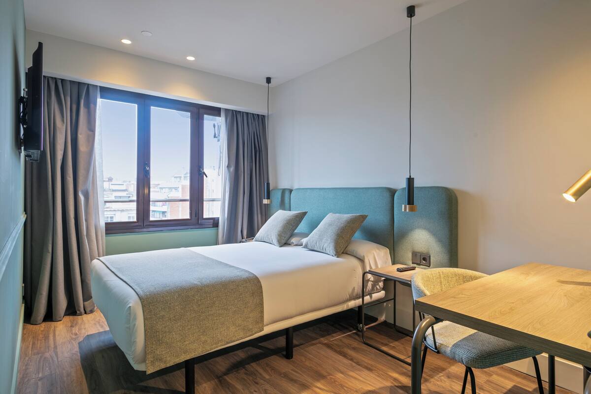Une chambre d’hôtel avec un lit, un bureau et une chaise.
