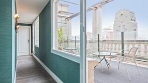 Un passadís amb vista a un balcó que té mobiliari exterior i un edifici històric al fons.
