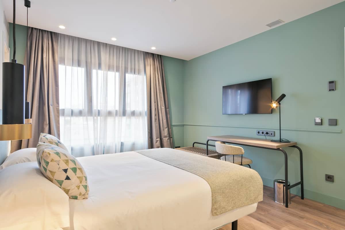 Une chambre d’hôtel moderne, dotée d’un grand lit, d’un bureau et d’une télévision.