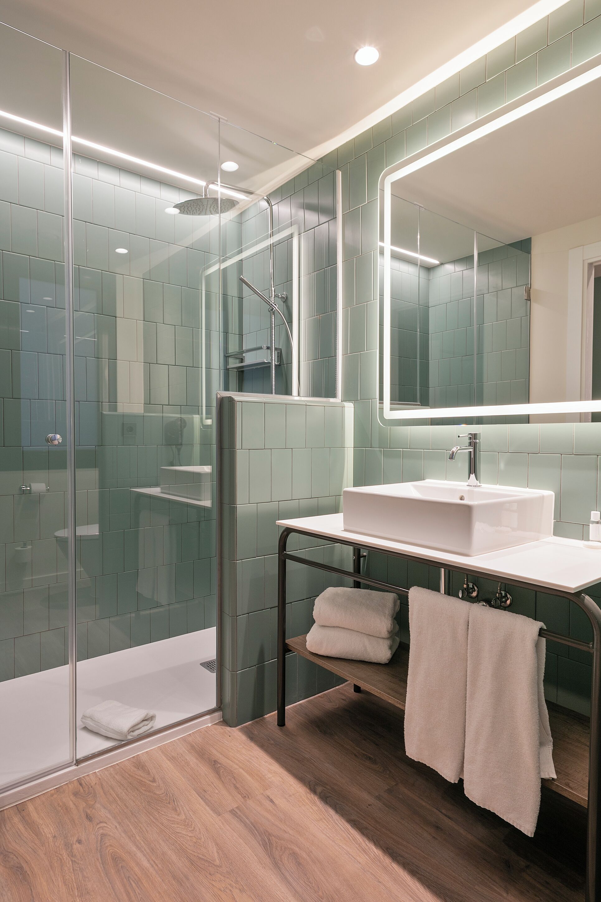A modern bathroom with a glass shower enclosure, a white sink, and a large mirror.
