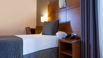 Ein Hotelzimmer mit Bett, Nachttisch, Lampe und Telefon.