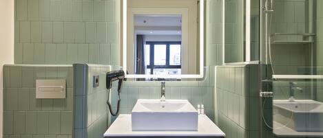 A bathroom with a white sink, a mirror, and a shower.