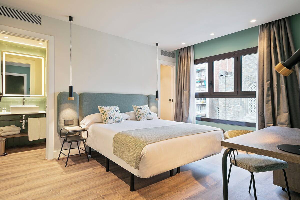 Une chambre d’hôtel moderne, dotée d’un grand lit, d’un bureau et d’une salle de bain.
