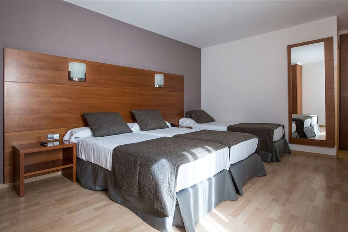 Une chambre d’hôtel avec un grand lit, une table de chevet et un miroir.