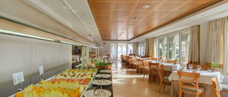 A buffet area with various food options, a seating area with tables and chairs, and large windows allowing natural light.