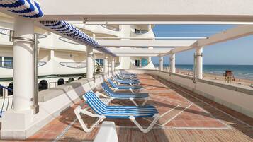 A deck with sun loungers and a view of the beach.