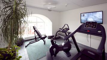Une salle de sport à domicile équipée de matériel d’exercice, d’un téléviseur et d’une grande fenêtre.